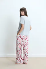 Pijama compuesto por una remera gris de manga corta con estampa frontal de corazón y un pantalón largo blanco con estampado de corazones rojos.