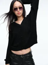 Cardigan de punto con hilo brillante, cuello en V y cierre frontal con botones. Presenta mangas largas con puños acanalados y un diseño de calce holgado.