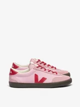 Championes Veja modelo Volley, de diseño inspirado en el voleibol de los años 70. Presentan una base de cuero en color rosa, con detalles en rojo en el logo lateral, talón y cordones. Cuentan con refuerzos de gamuza en la puntera y una suela de goma en color marrón oscuro.