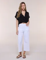 Pantalón capri blanco de corte recto y largo crop, con cintura alta y bolsillos delanteros aplicados estilo parche con detalle festoneado.