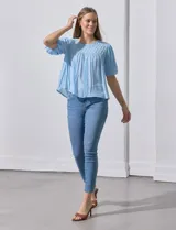 Blusa blanca de gasa marca Zac & Rachel, con frunces en la parte delantera, mangas cortas con puño elastizado, abertura central en la espalda y botón.