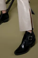Botin de cuero color bordeaux con diseño de textura combinada, punta cuadrada y hebilla metálica lateral.