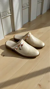 Sandalias cerradas tipo mules de cuero color natural, con detalle de aplique pintado a mano en tonos tierra y herraje metálico triangular en el lateral.