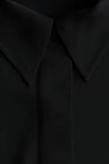 Vestido midi negro con cuello camisero y tapeta con botones ocultos, de mangas largas raglán con puños anchos y costura fruncida en la cadera con falda de vuelo leve.
