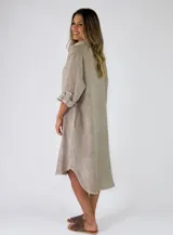 Camisola midi confeccionada en lino color gris, con diseño amplio y fluido, cuello camisero, cierre frontal con botones y mangas largas con presilla para arremangar.