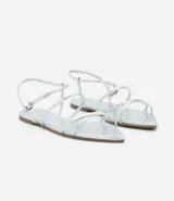 Sandalia plana dorada con tiras finas y cierre con hebilla en el tobillo.