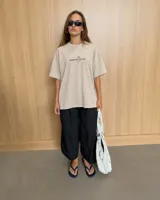 Remera oversize color beige de corte holgado, con estampa en la espalda que representa un esqueleto dentro de un ataúd con rayos oscuros y texto descriptivo.