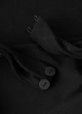 Vestido largo negro de corte slim, con cuello drapeado, sin mangas y detalle de fruncido lateral con caída de tela en la cadera.