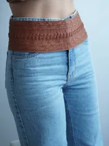 Faja de cuero color camel con diseño trenzado horizontal y lazo lateral ajustable con flecos.