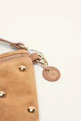 Bandolera de gamuza color marrón con diseño de media luna, decorada con tachas metálicas doradas distribuidas en el frente. Cuenta con cierre superior metálico y correa larga ajustable para llevar cruzada.