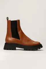 Bota Chelsea color verde militar de cuero, con elásticos laterales negros, tirador trasero y suela track negra.