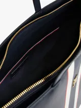 Cartera tipo tote de Tommy Hilfiger en color azul marino, con diseño de franjas verticales en el centro en tonos blanco, azul y rojo. Presenta logo metalizado dorado en la parte frontal y doble asa superior.