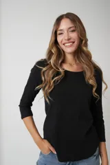 Remera básica de algodón con cuello redondo y mangas tres cuartos. Presenta un corte ajustado y ruedo redondeado.