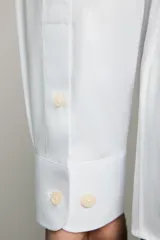 Camisa de corte regular fit color celeste, confeccionada en tejido fácil de planchar. Cuenta con cuello italiano abierto, manga larga con puño abotonado y cierre frontal con botonadura.