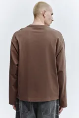 Remera de manga larga en punto pesado, con cuello redondo, hombros caídos y bajo recto. Presenta un corte oversized para una silueta holgada.