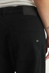 Pantalón de jean negro, de corte holgado desde la cadera hasta el bajo, con tiro medio y cierre frontal con botones.