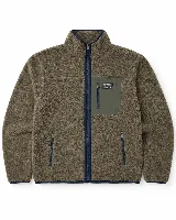 Campera de sherpa color marrón con cierre frontal, cuello alto y bolsillo en el pecho con cierre. Presenta detalles en color azul marino en los bordes y cierres, y un parche decorativo en el bolsillo superior.