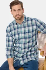 Camisa de manga larga confeccionada en una mezcla de lino y algodón, con diseño a cuadros en tonos verdes, azules y blancos. Presenta cuello clásico, cierre frontal con botones y un bolsillo en el pecho con el logo de la marca bordado.