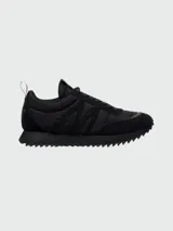 Zapatillas Moncler modelo Pacey de color negro, con diseño de caña baja y suela dentada. Presentan detalles en gamuza y nylon, y una presilla trasera con los colores tricolores de la marca.