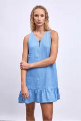 Vestido corto blanco sin mangas, con escote en V y detalle de broche dorado en el centro. La falda tiene un volado en el ruedo.