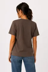 Remera de algodón color blanco off-white, de manga corta, cuello redondo a la base y corte holgado. Presenta un estampado frontal con diseño de corazón en tonos marrones y azules, con detalles de strass y texto.