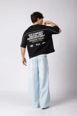 Remera gris oscuro de corte boxy, con mangas cortas y cuello redondo. Cuenta con un diseño gráfico frontal con líneas blancas y la palabra 'CONCEPT' estampada.