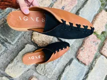 Zapatos tipo mules de punta cerrada y talón abierto, con diseño bicolor que combina cuero metalizado dorado y tono mostaza. Presentan detalles de costuras cruzadas en contraste sobre el empeine y suela baja.