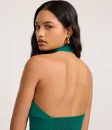 Top cropped de crepé color verde esmeralda, con escote halter y cuello alto. Presenta un canesú fruncido en la cintura que ajusta la prenda al cuerpo.