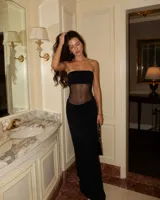Vestido largo negro de corte sirena con diseño strapless y sección semitransparente en el abdomen.