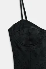 Vestido corto de estilo lencero con escote en pico y copas estructuradas. Presenta tirantes finos ajustables y un diseño de tejido jacquard con estampado floral tono sobre tono.