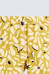 Bañador de hombre de tejido técnico ripstop, color mostaza con estampado floral abstracto en blanco y negro. Presenta cintura elástica ajustable con cordón, bolsillos laterales y bolsillo trasero de plastrón.