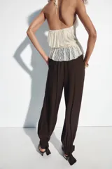 Pantalón bombacho de tiro alto, color marrón, con efecto arrugado y cintura elástica en la espalda. Cuenta con pinzas delanteras, bolsillos frontales, pernera abullonada y puños acabados en lazo.