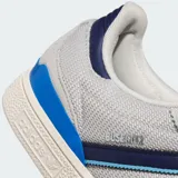 Championes Adidas Busenitz color gris con detalles en azul marino y celeste. Presentan las tres tiras características de la marca en los laterales, capellada de gamuza y suela de goma.