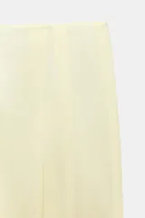 Pantalón de tiro medio de pierna ancha color amarillo pastel, confeccionado con mezcla de lino. Cuenta con bolsillos laterales ocultos, pliegues delanteros y cierre frontal con cremallera, botón y ganchos metálicos.