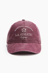 Gorra de sarga de algodón bordada en color bordó, con efecto lavado, visera curva y cierre metálico ajustable en la parte posterior.