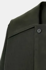 Trench corto de Zara, confeccionado en mezcla de lyocell, color verde militar. Presenta cuello solapa, manga larga con hombro caído y puños con trabilla. Incluye bolsillos delanteros de plastrón, cierre frontal cruzado con botón y cinturón de lazada en el mismo tejido.