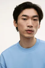 Buzo azul claro de tejido de mezcla de algodón, con interior cepillado suave, cuello redondo ribeteado, hombros caídos y remate acanalado ancho en puños y bajo. Corte holgado.