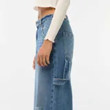 Jean baggy de tiro medio color azul claro con efecto desteñido y roturas en la rodilla izquierda. Presenta bolsillos laterales estilo carpintero y presillas para cinturón.