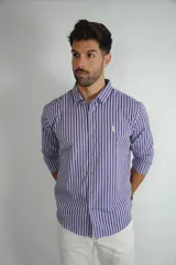 Camisa de manga larga con estampado de rayas verticales en tonos azul, violeta y rojo. Presenta cuello clásico, cierre frontal con botones y logo bordado en el pecho.