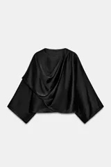 Blusa negra de satén con escote fluido, diseño drapeado en el frente y mangas largas anchas. Presenta un bajo asimétrico y una caída suave y elegante.