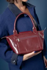 Cartera pequeña de mano tipo tote, confeccionada en gamuza color azul, con solapa y asas en cuero sintético con textura de reptil. Incluye cierre superior y correa larga ajustable y extraíble.