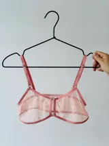 Top de lencería confeccionado en microtul color salmón con estampado de pequeñas flores. Presenta un diseño con aberturas frontales unidas por herrajes metálicos, breteles regulables y terminaciones en cinta elástica al tono.