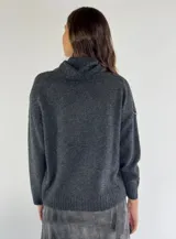 Sweater de punto color beige con cuello alto, diseño de rombos en relieve y detalle de lentejuelas aplicadas en el frente.
