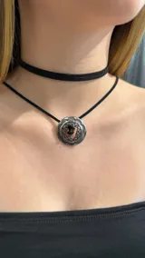 Choker doble de cordón negro con un dije circular metálico de estilo étnico con diseño calado y grabado.