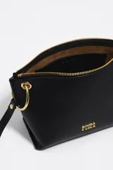 Bolso bandolera de estructura rígida y tamaño mediano confeccionado en piel vacuna. Presenta asa regulable, cierre con cremallera, bolsillo interior y logo metálico de la marca. Incluye un charm decorativo con borlas en el lateral y acabados metálicos.