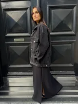 Campera clásica de jean negra con cuello camisero, bolsillos frontales y detalles de brillos plateados.