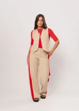 Pantalón beige de tiro alto con bolsillos delanteros y traseros, cierre frontal con cremallera y botón, y detalle de pespuntes rojos en los laterales.