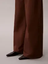 Pantalón chino de pierna súper ancha color marrón, tiro alto, con diseño de cinco bolsillos, cierre de botón y cremallera, y detalles distintivos de la marca Calvin Klein.