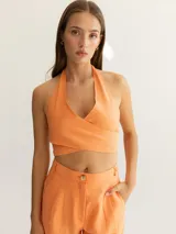 Top color naranja de lino, estilo halter con espalda descubierta y diseño cruzado en el frente.