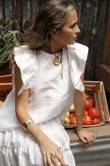 Blusa blanca de lino con volados en los hombros y pespuntes en color beige.